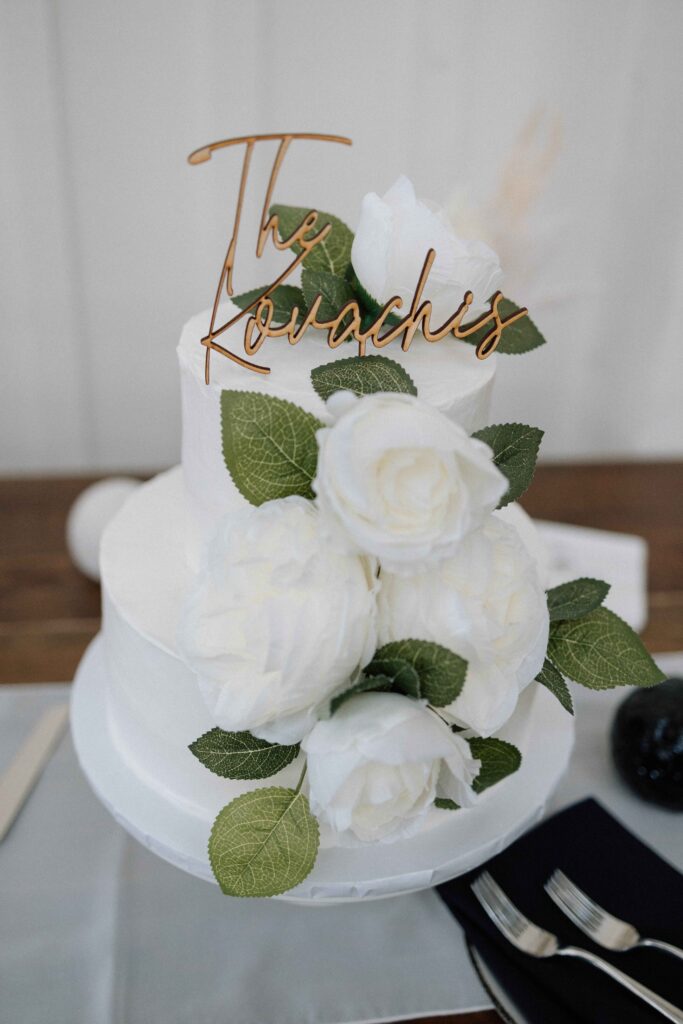 Simple and elegant wedding cake with white roses and greenery.