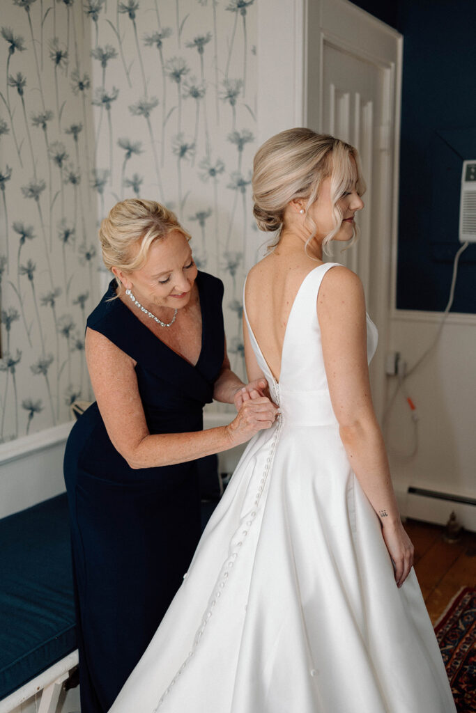 Bride's mother button up her wedding dress.