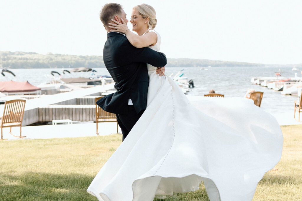 Groom swinging his bride around with  boats in the background as they pose for wedding photos while following their wedding photography timeline.