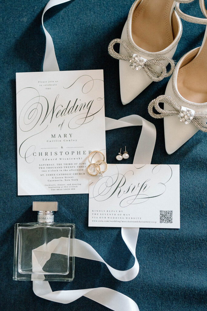 Detail shot of wedding stationary, heels, perfume, and jewelry. 