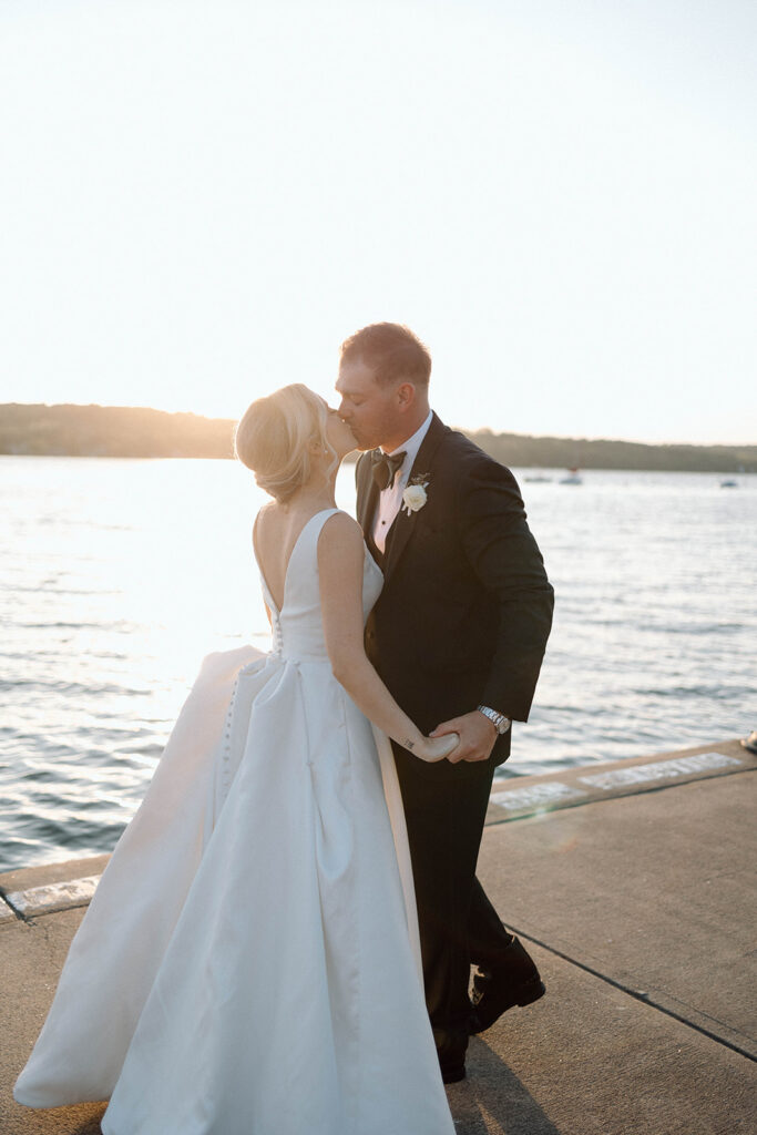 Bride and groom kissing on a dock during their wedding portraits as part of their wedding photography timeline.