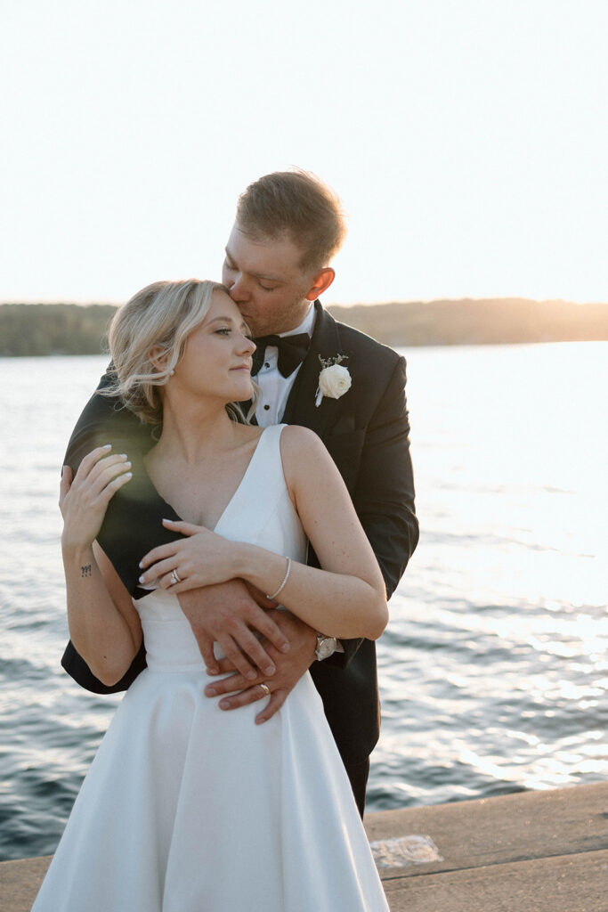 Newlyweds posing during sunset by a lake.