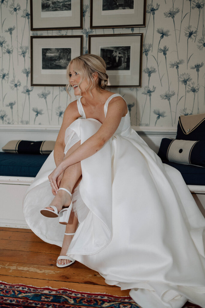 Bride following her wedding photography timeline by getting ready and putting on her heels.