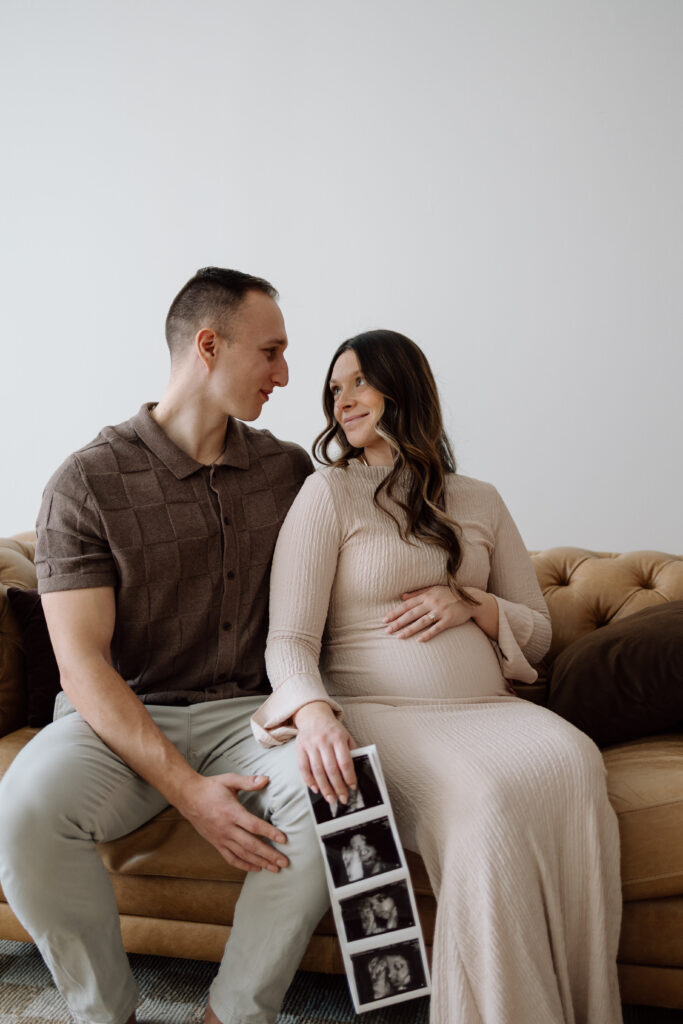 Husband and wife holding their ultrasound photos for their maternity photos.