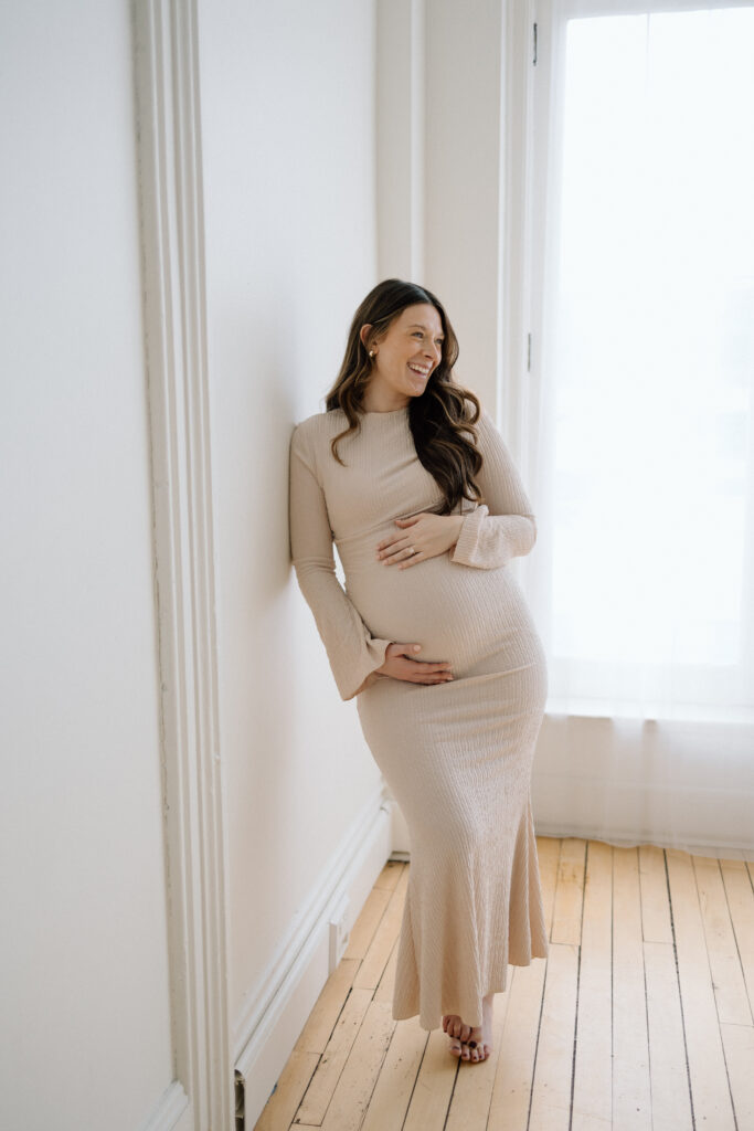 Beautiful woman smiling and holding her pregnant belly at the Lincoln Loft & Studio. 
