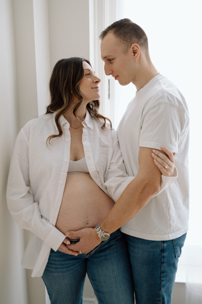 Husband and wife looking into each others eyes during their maternity photos.