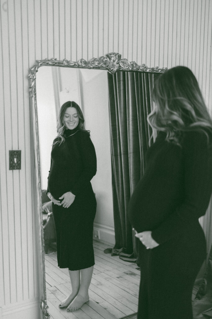 Woman looking at her pregnant belly in the mirror and smiling. 