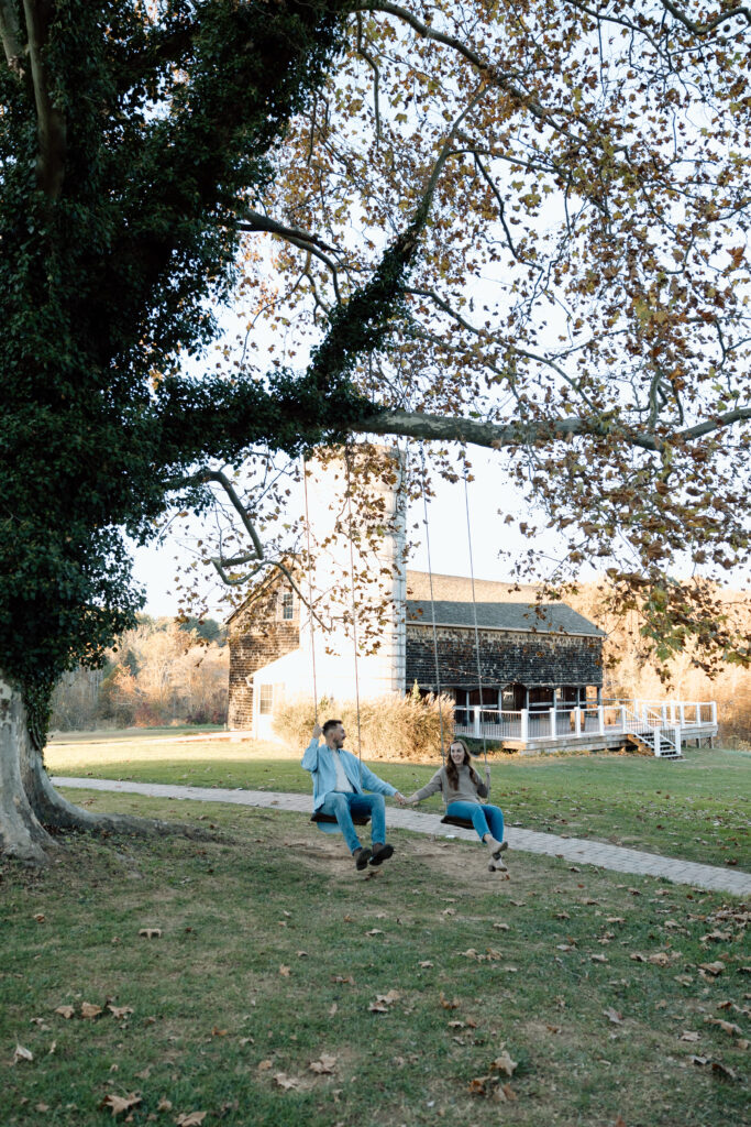 An engaged couple swinging on swings. 