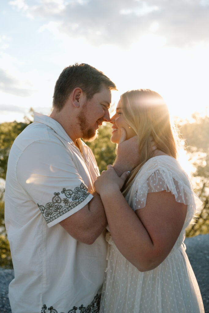 A couple about to kiss with the sun setting behind them.