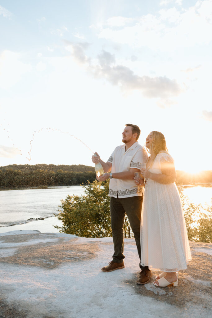 Engaged couple popping champagne during their engagement shoot. 