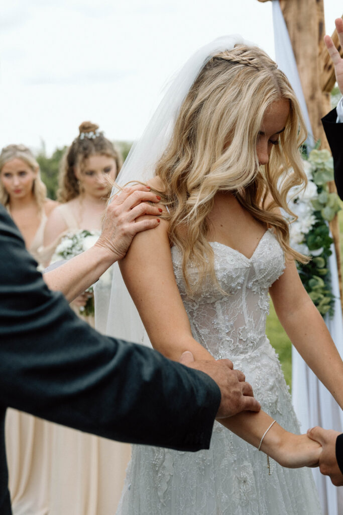 Guests hands on the bride as they pray over the bride and groom during their reception. 