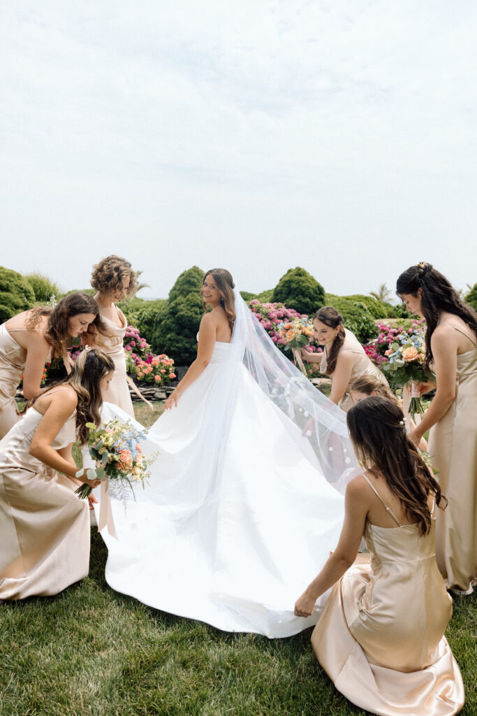 Editorial wedding photography of bridesmaids helping the bride adjust her wedding dress and veil.