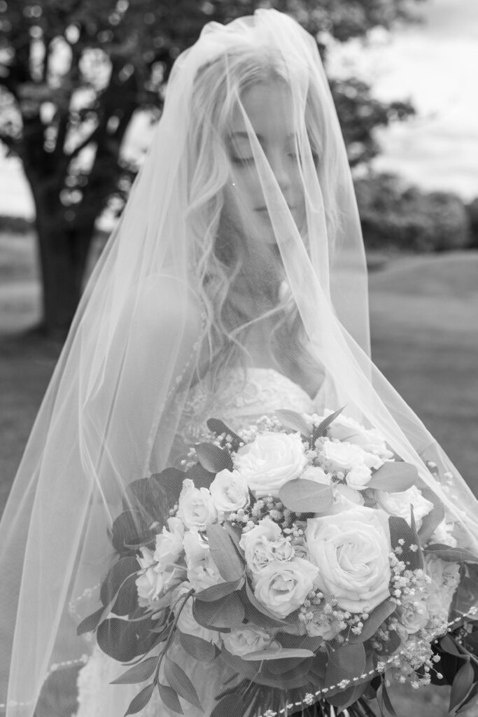 Bride looking at her bouquet under her veil for editorial wedding photography.