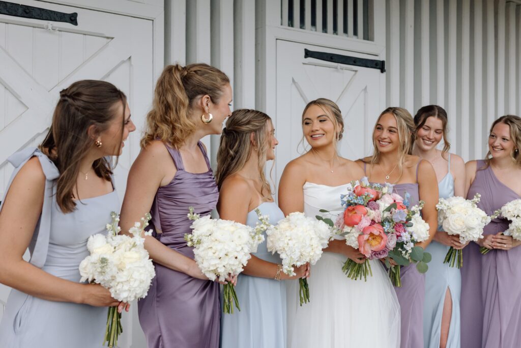 Bridal party smiling together holding flowers.