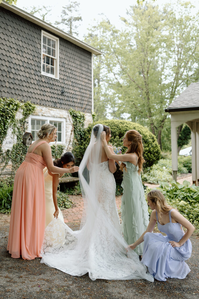Bridesmaids helping the bride fix her dress and veil. 