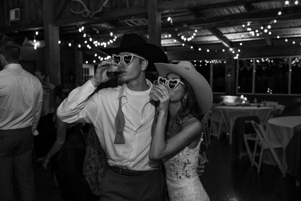 Bride and groom taking a drink while wearing heart sunglasses.