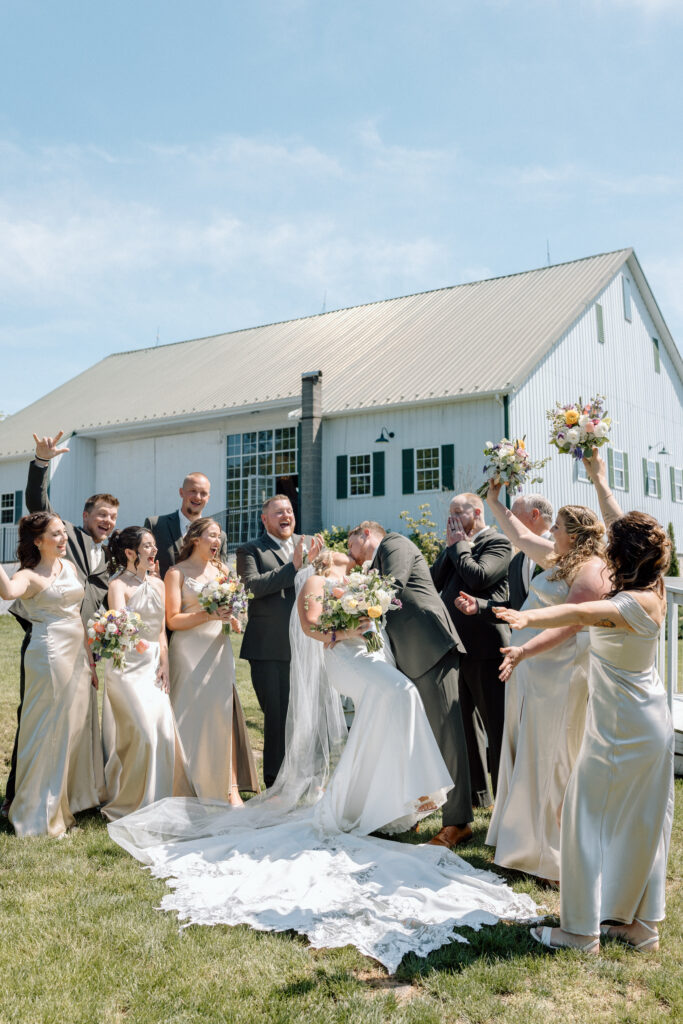 Wedding party cheering as the bride and groom kiss outside the Goldfish Barn Event Center, one of the best Pennsylvania wedding venues.