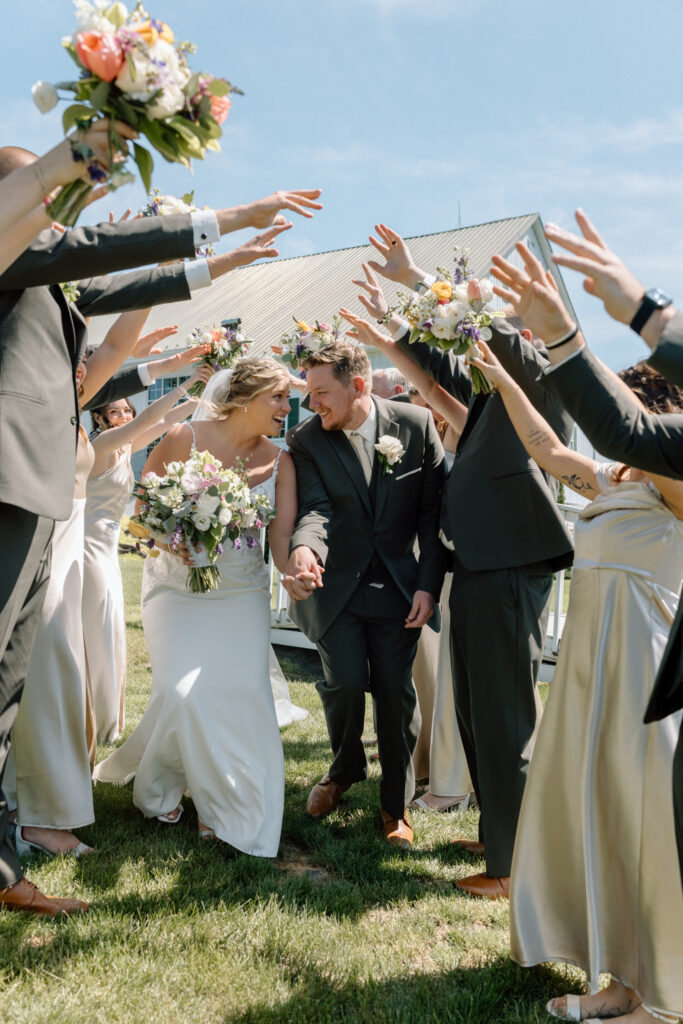 Newlyweds running through the wedding party with their hands in the air. 