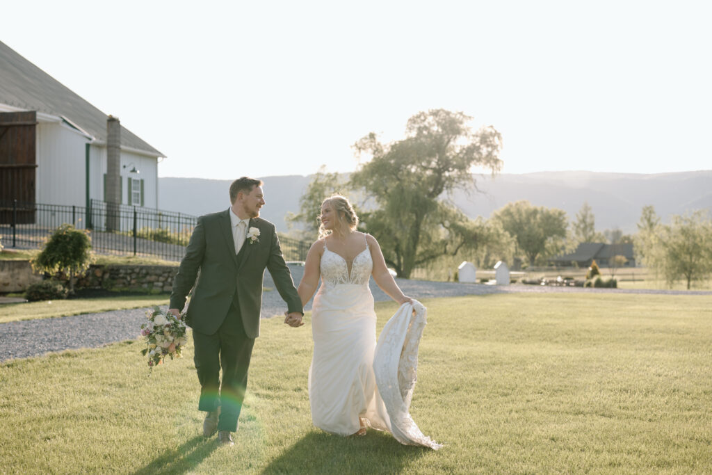 Newlyweds walking hand in hand with mountains in the background.