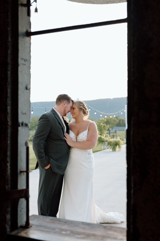 Bride and groom holding each other romantically through a window at the Goldfish Barn Event Center in Pennsylvania. 