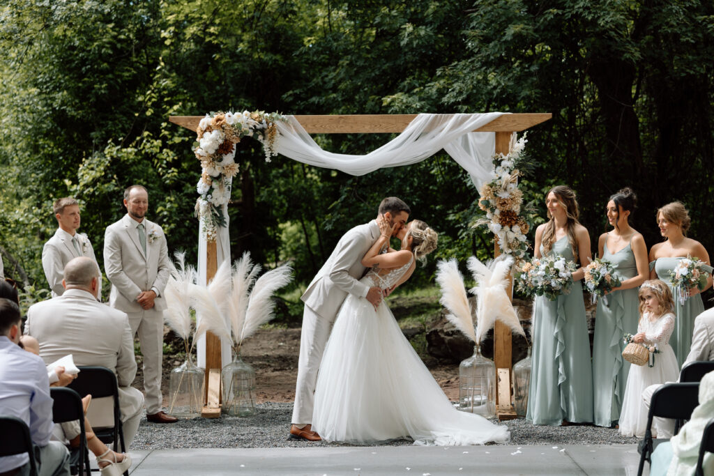 Bride and groom kissing during their ceremony at the River Bend Venue, one of the best Pennsylvania wedding venues.