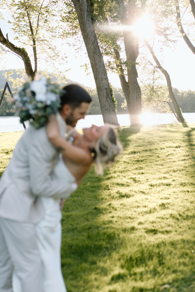 Bride and groom holding each other in front of the lake and trees at The River Bend Venue in PA.