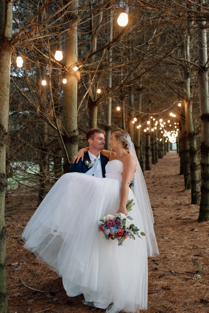 Groom carrying his bride in the forest at Stone Gables Estate in PA.