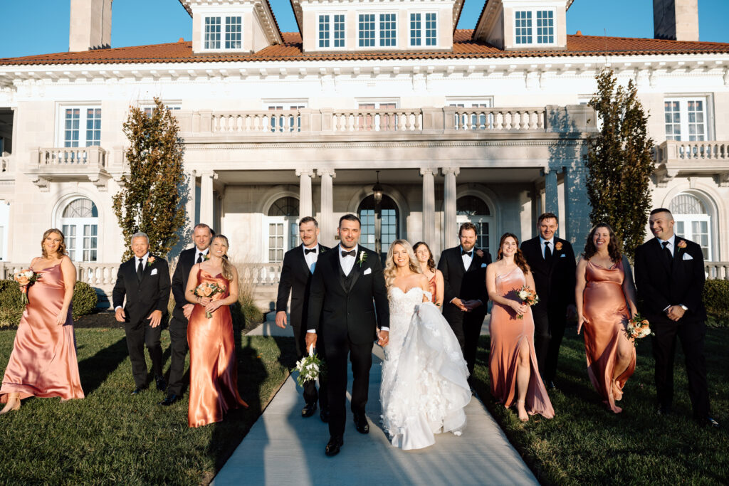 Bridal party walking and smiling in front of King Mansion in PA.