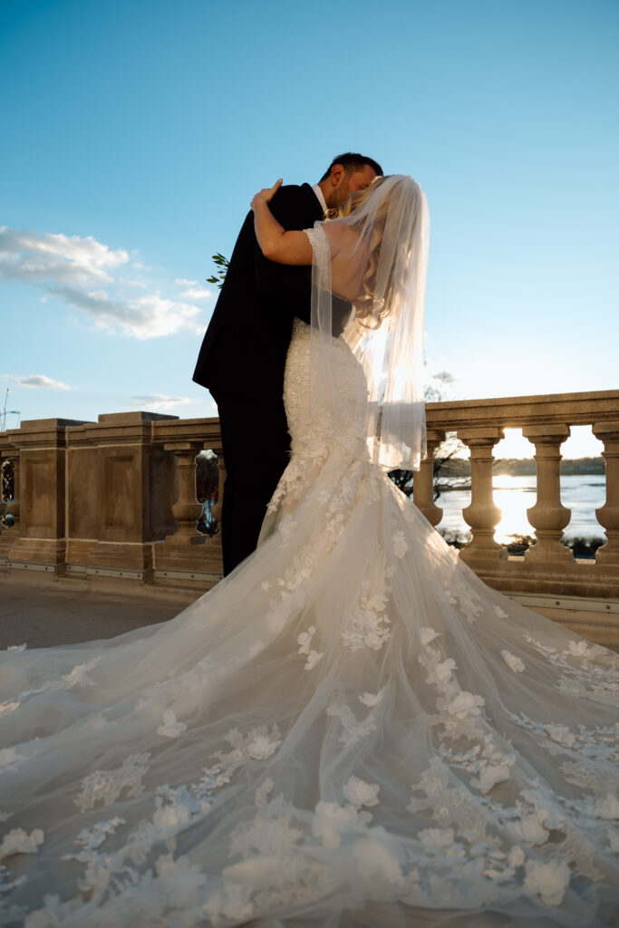 Bride and groom kissing on a balcony overlooking a lake in Pennsylvania. 