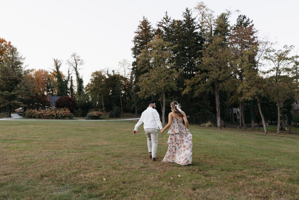 Engaged couple running in an open field at Historic Shady Lane. 