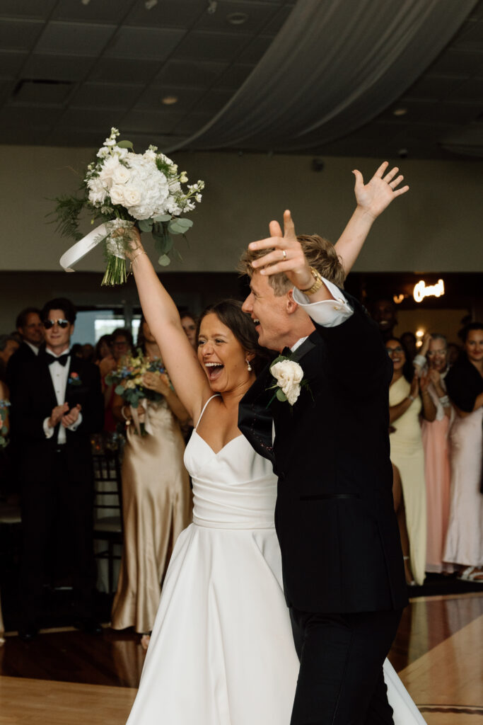Documentary style wedding photography of newlyweds entering their wedding reception full of joy.