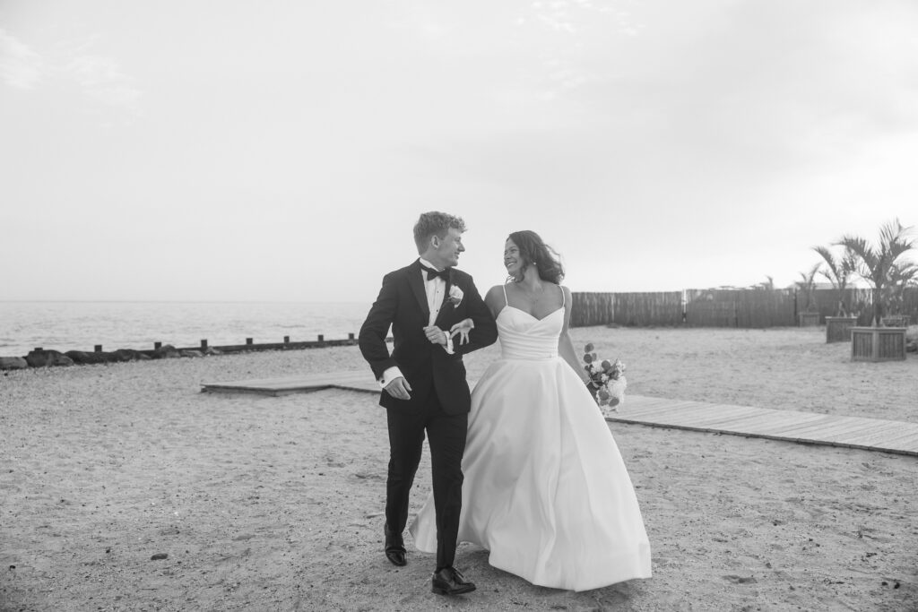 Documentary style wedding photography of newlyweds running together on the beach.