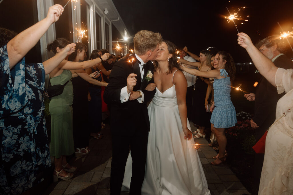 Bride and groom kissing during their sparkler exit. 