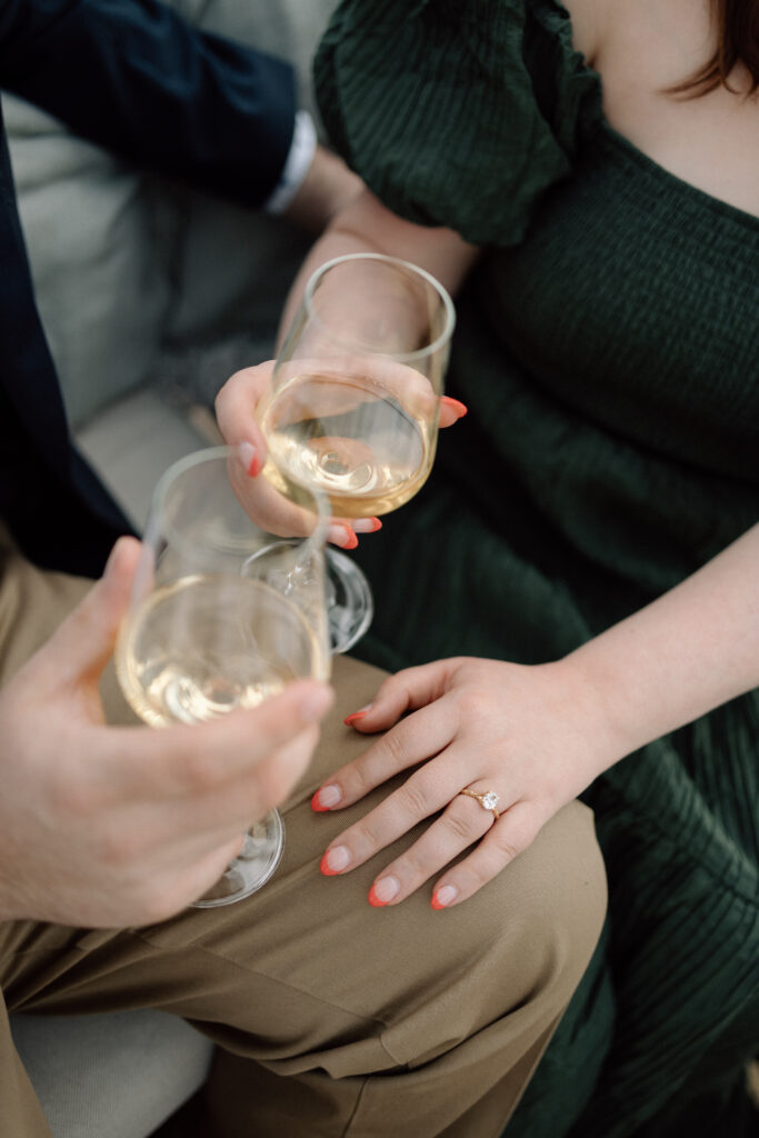 Engaged couple drinking wine with a close up on her engagement ring.