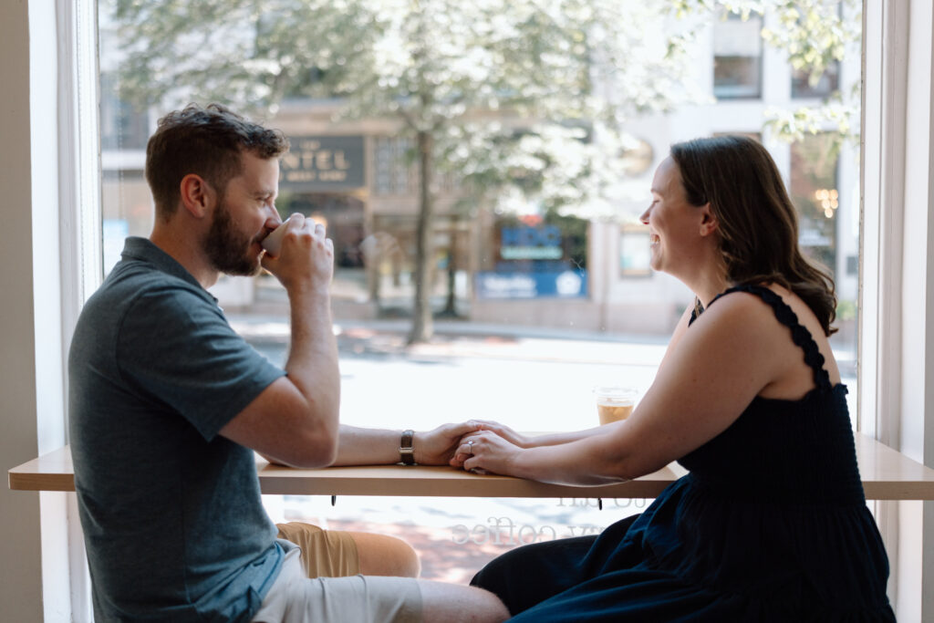 Couple at a coffee shop which is one of their favorite engagement photo locations.