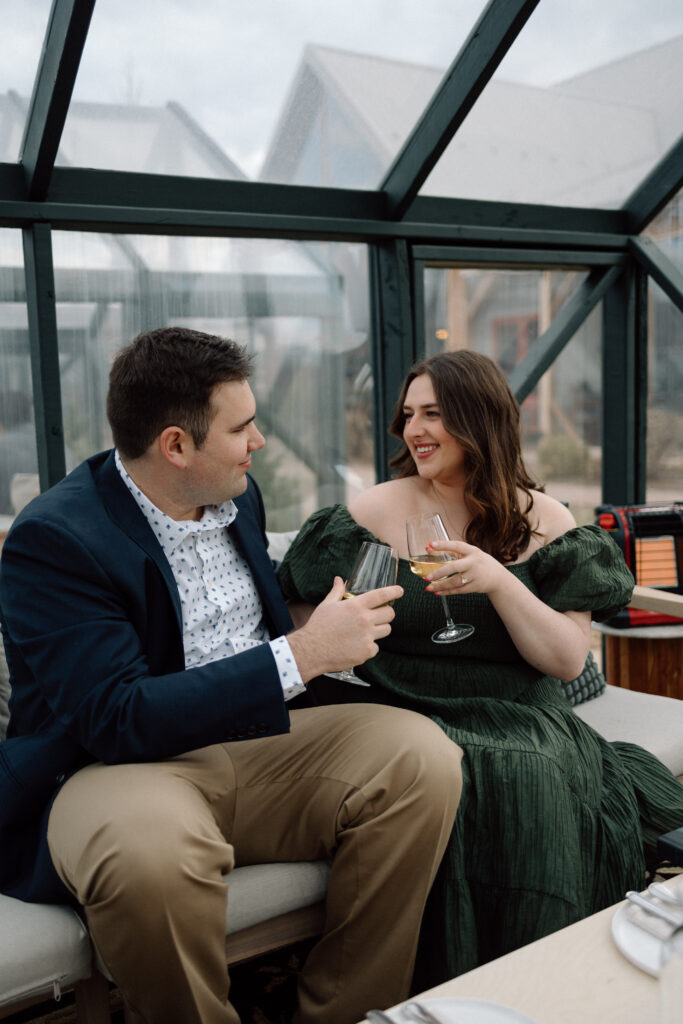 A couple at one of their favorite engagement photo locations drinking while together at a winery.